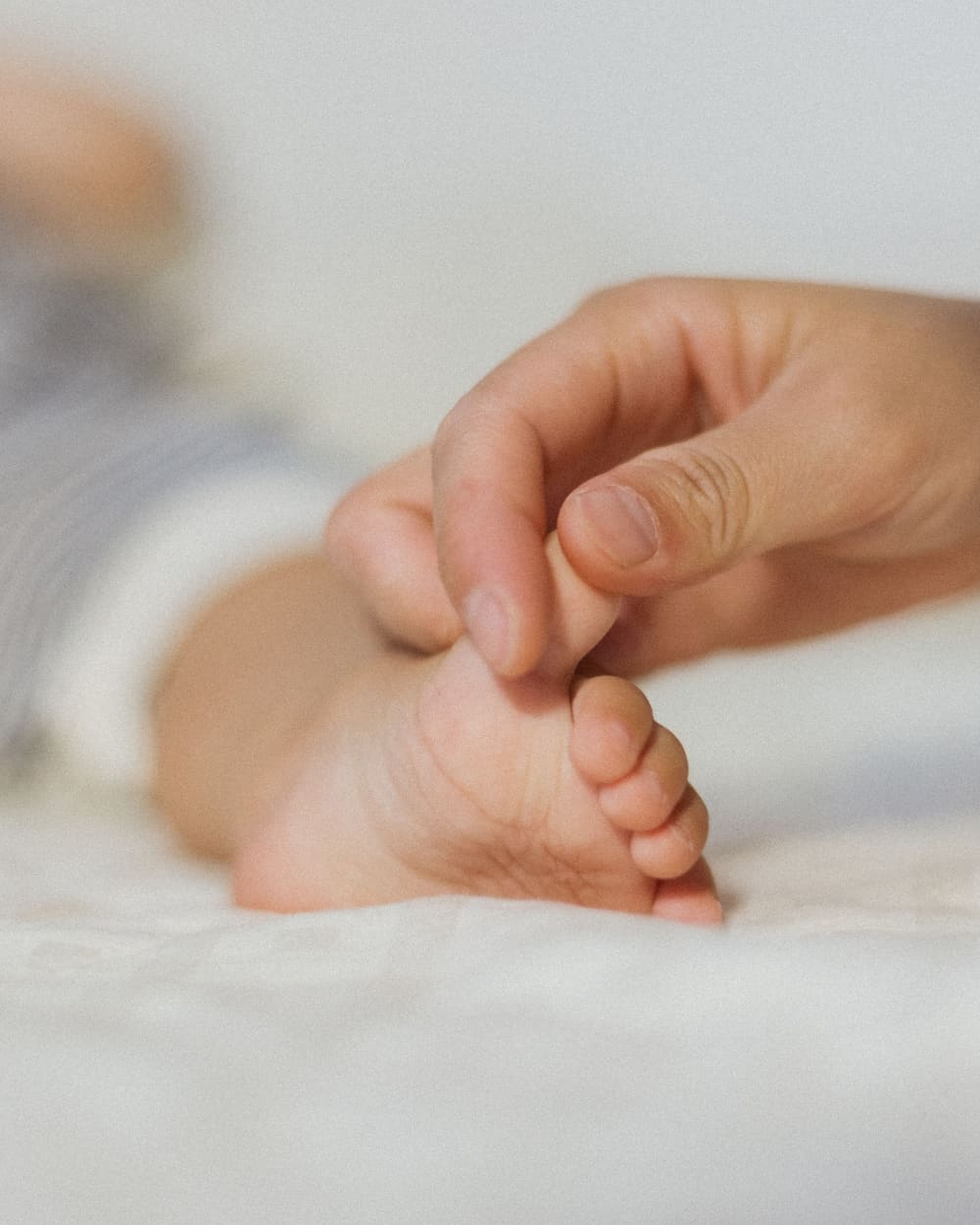 A new parent holding their infant's foot, a tender moment representing the family GuardTies helps protect