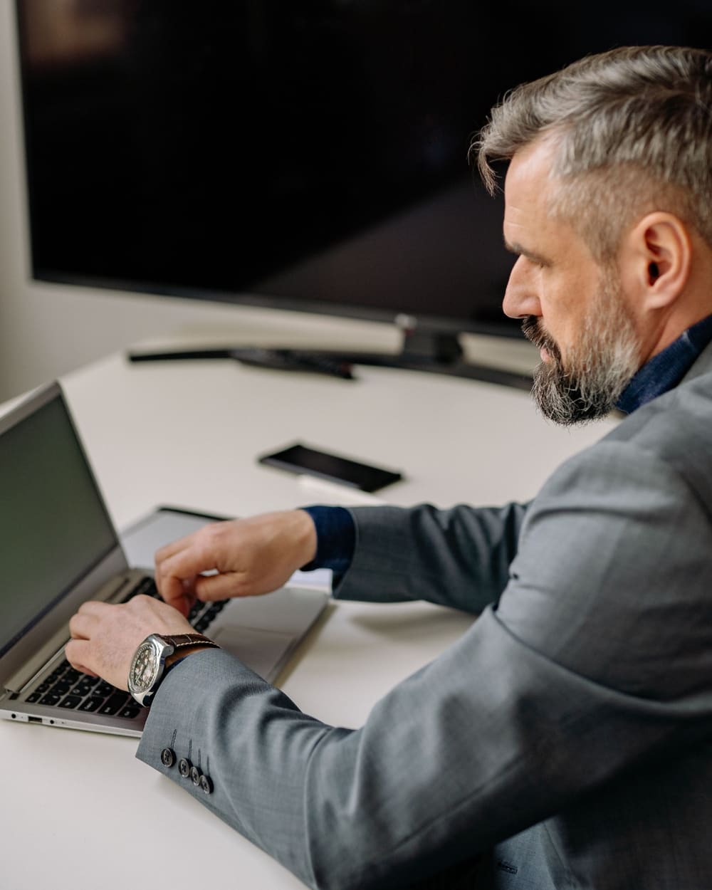 A businessman in a suit working on his laptop, managing his wealth and assets